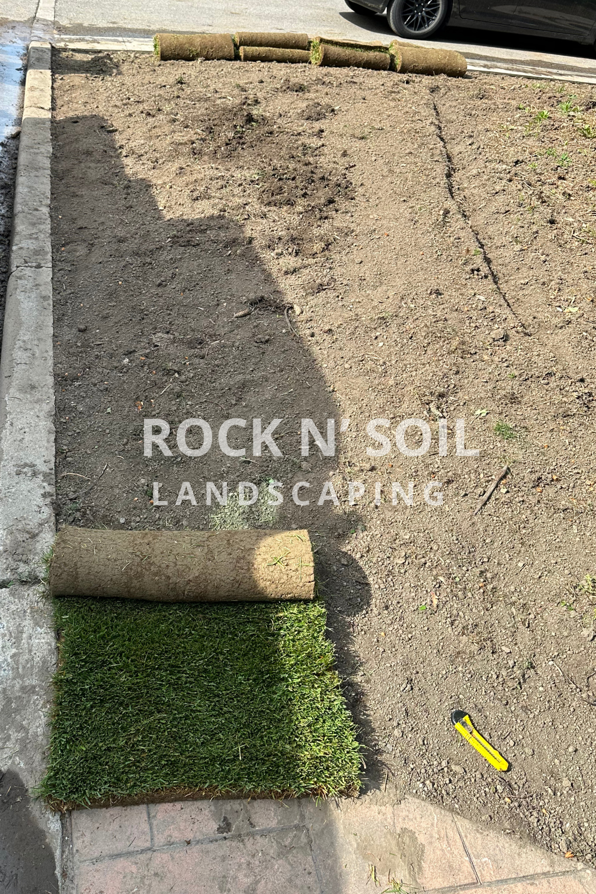 before and after photos, this is the before photo of a sod installation. In this picture the first roll of sod is being laid