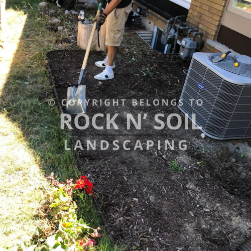 New flower bed preparation with soil for gardening, adjacent to a residential home